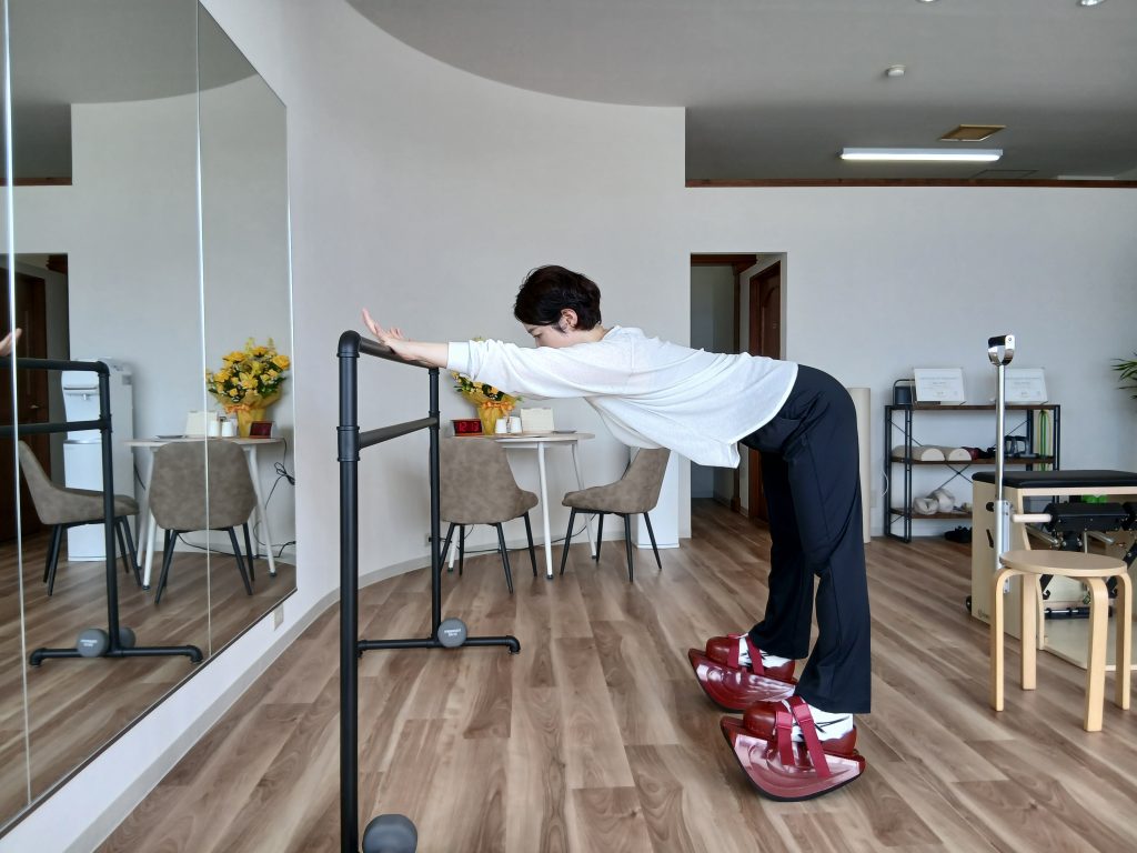 マスターストレッチを履き、バーに手を伸ばして上体を前方へ倒す女性