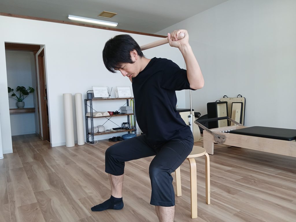 棒を使ったラットプルダウンで、上半身が前に傾いている様子